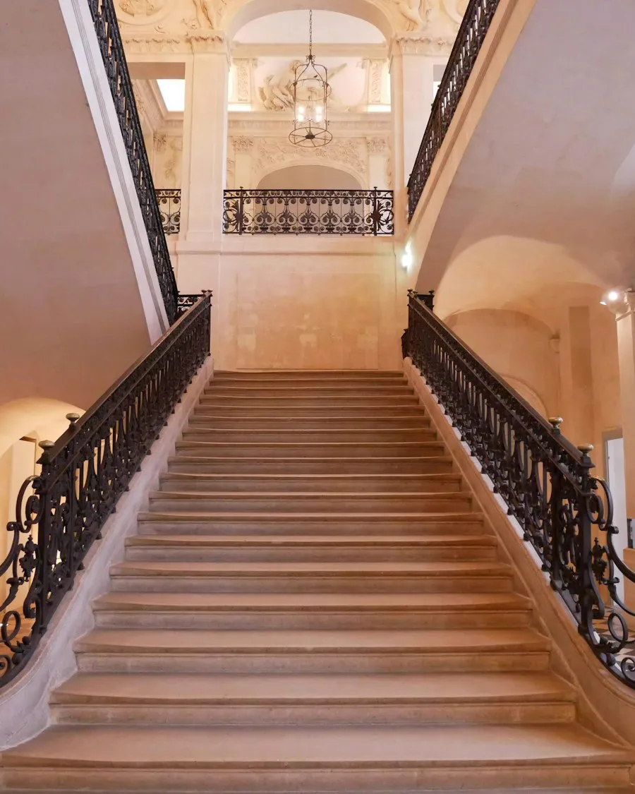 Le grand escalier en pierre d'un hôtel particulier, sa rampe en fer forgé