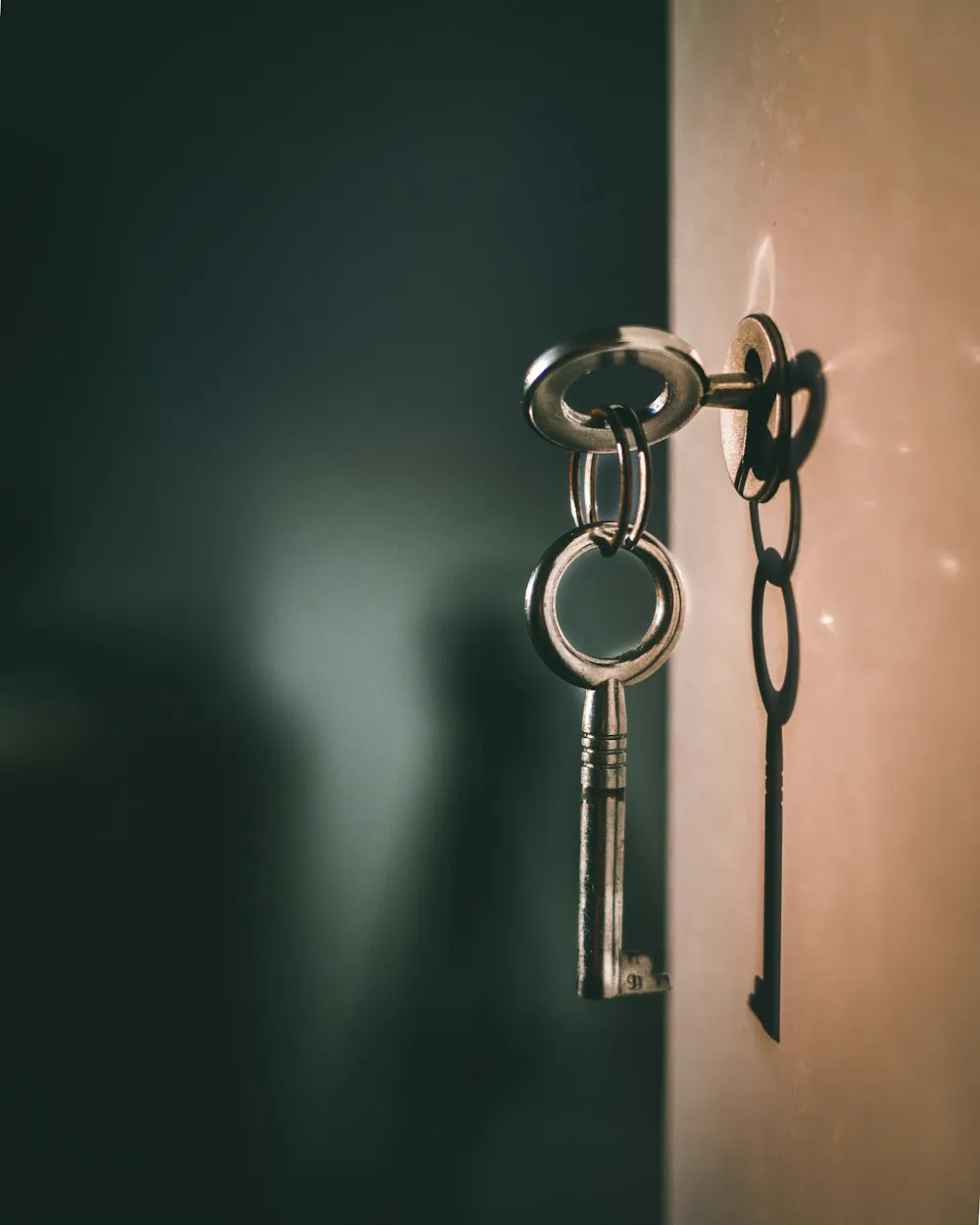 Des clés anciennes accrochées à la serrure d'une porte vert sombre