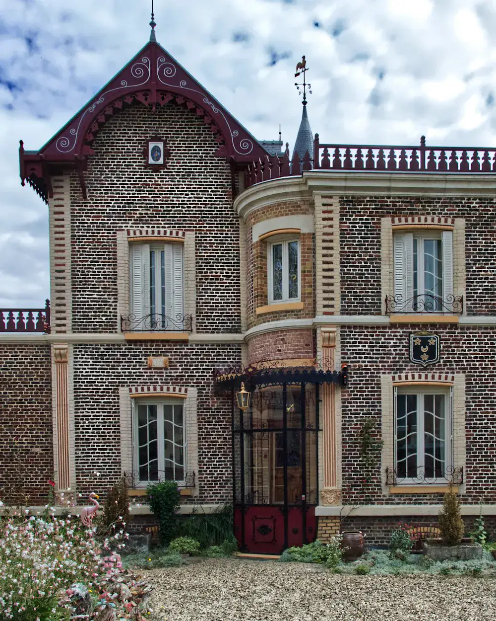 Une villa en pierre meulière et briques, avec sa tourelle et son jardin fleuri