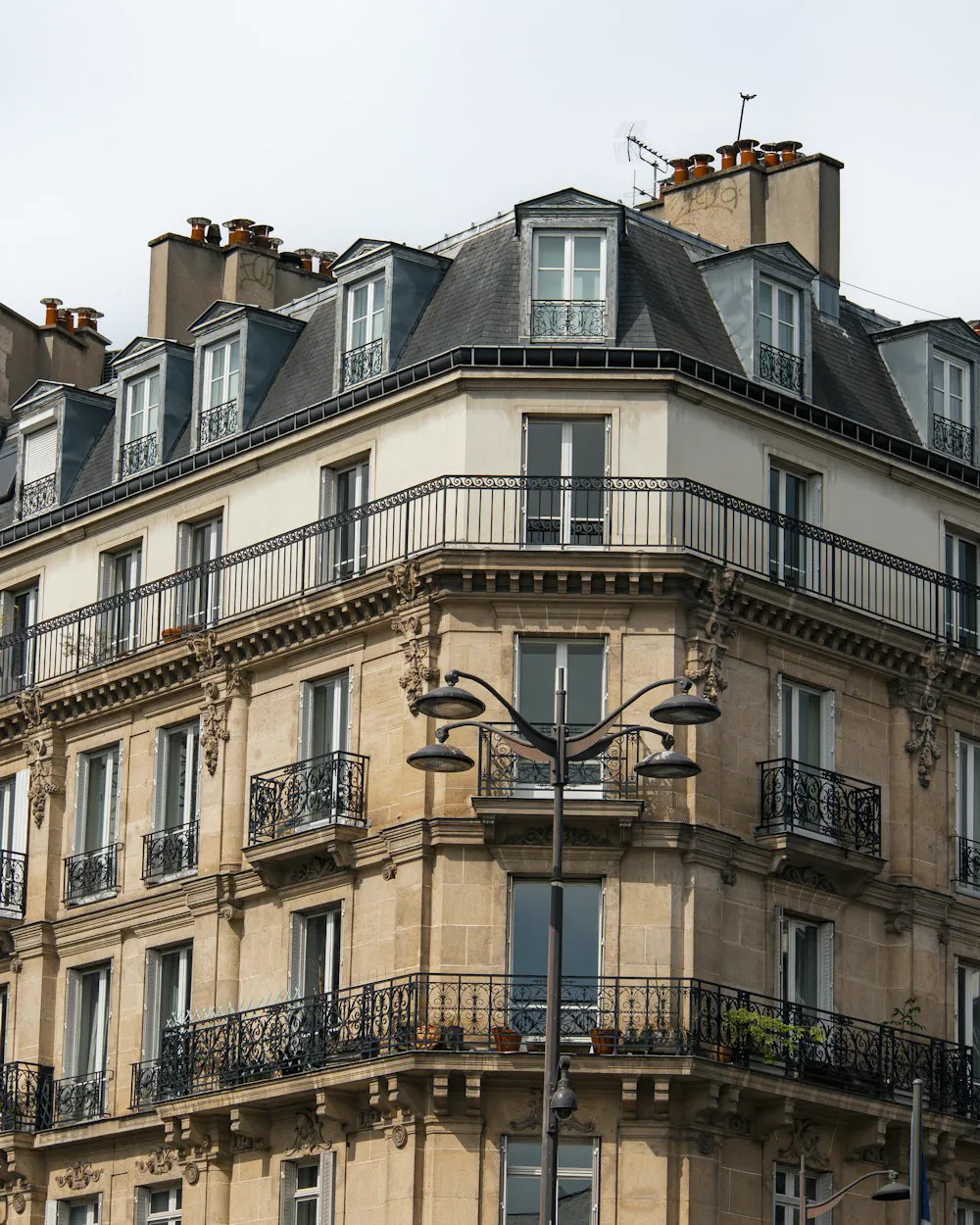 L'angle d'un immeuble haussmannien en pierre, balcons en fer forgé