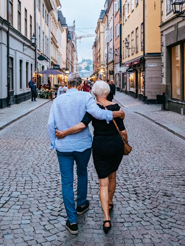 Un couple de retraités qui se promène bras dessus bras dessous dans une rue pavée
