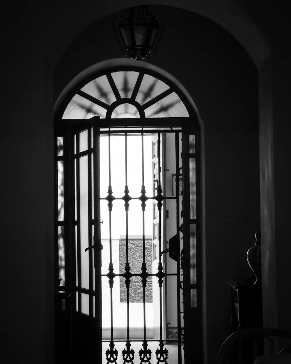 Une porte en fer forgé vue depuis le hall d'un immeuble ancien