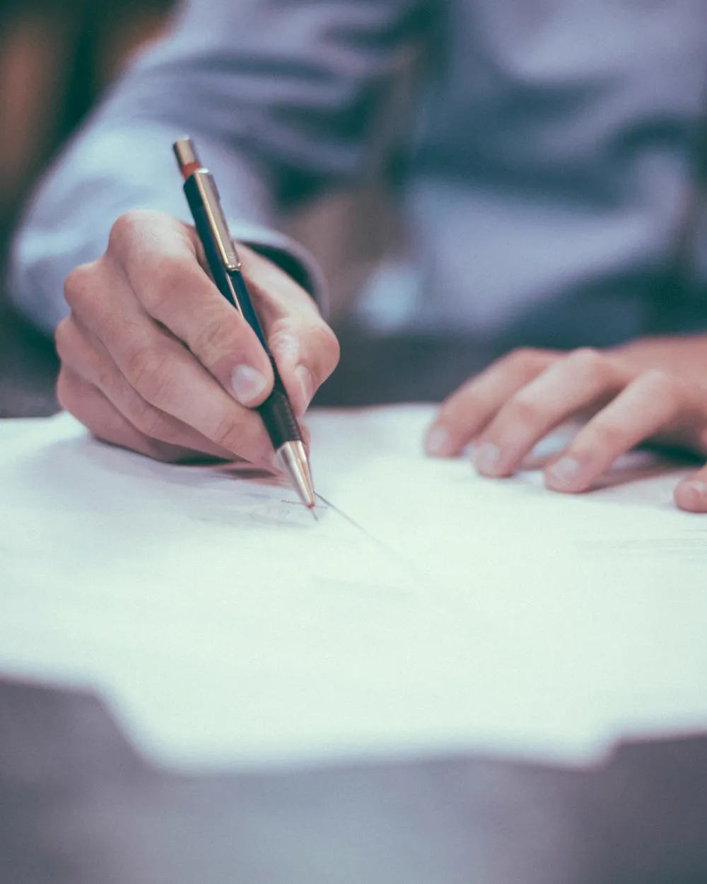 Une main signe un document au stylo